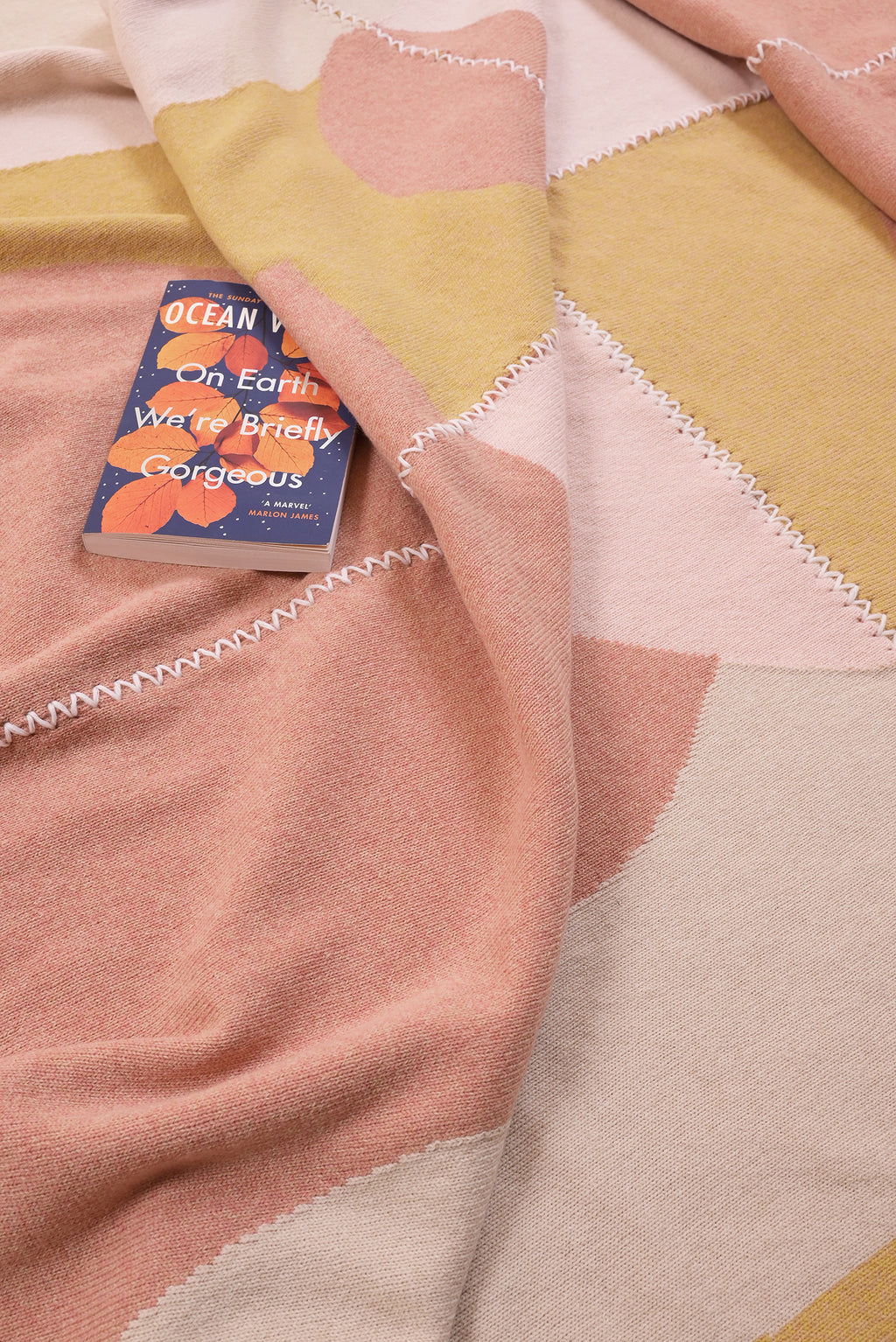 Colorful knit wool blanket with a book titled 'Ocean' on top