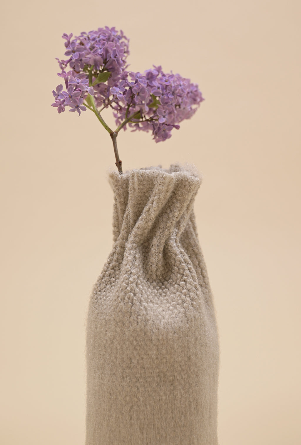 close-up of beige knit textile vase in brushed silk and organic cotton with flower
