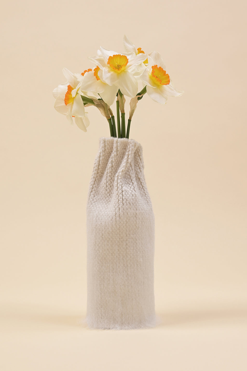 front view of off-white knit textile vase in brushed silk and organic cotton with flower