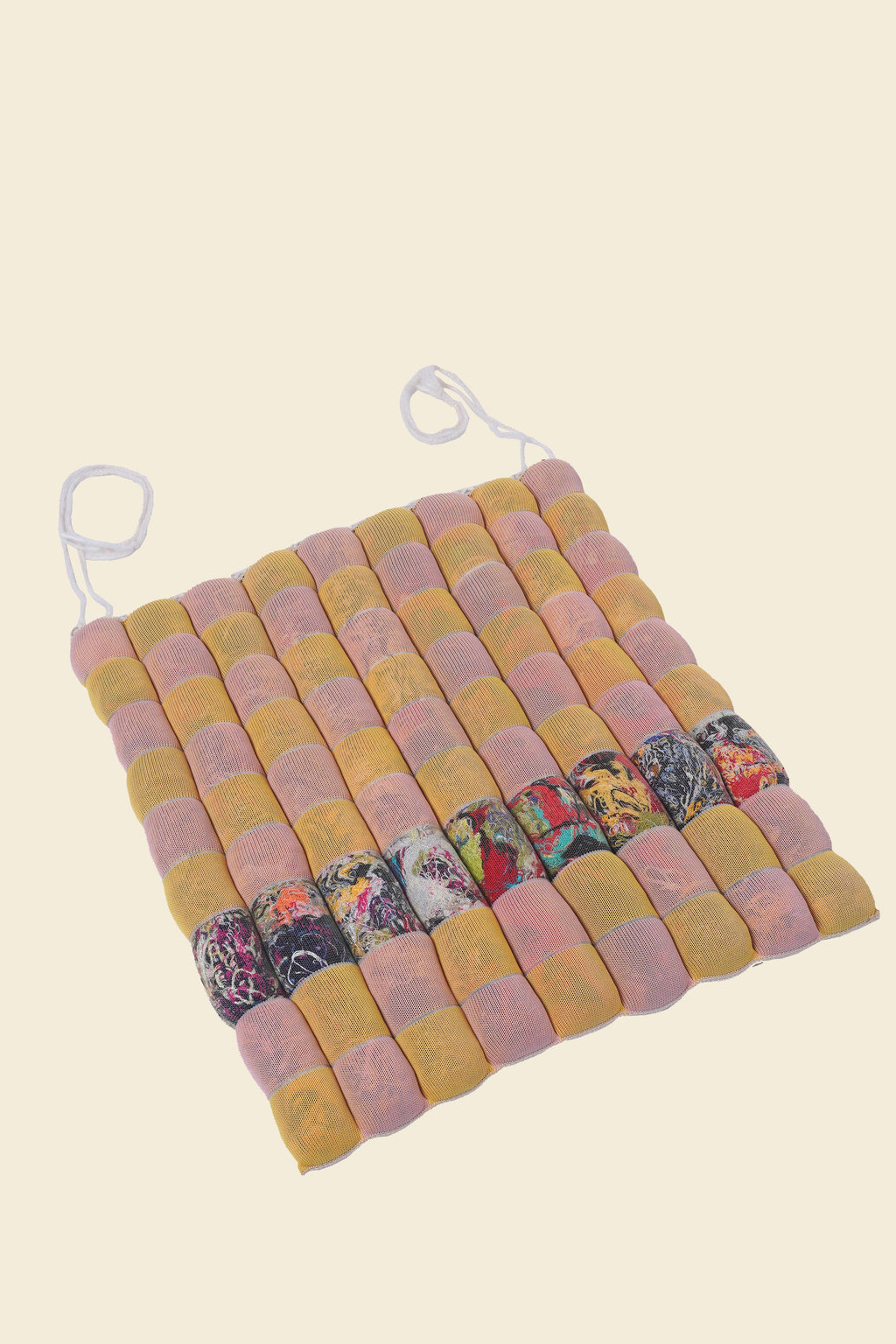 front view of yellow/pink knit checkered seat cushion with upcycled materials with beige background 