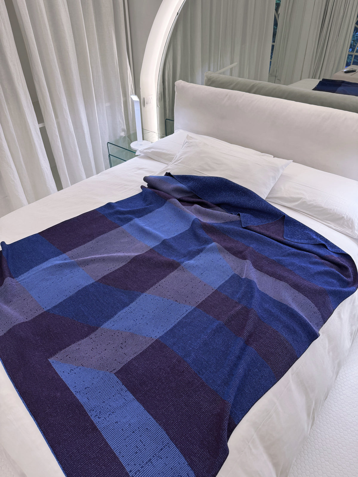 geometric ikat knit blanket in blue and purple folded on a bed, wool and organic cotton [blue/purple] [open]