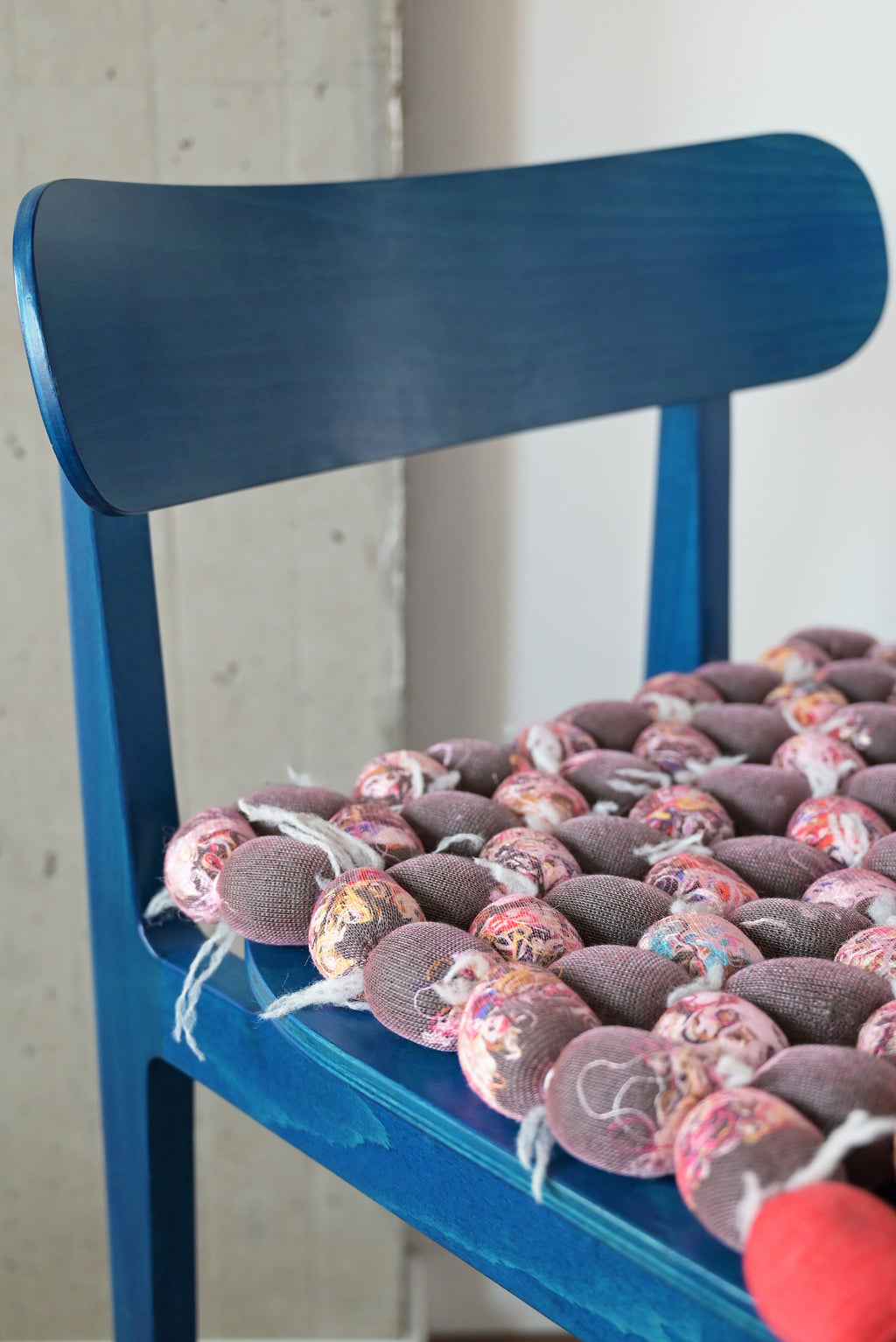 side view of hand-knotted knit seat cushion with transparent cover filled with upcycled materials on a chair