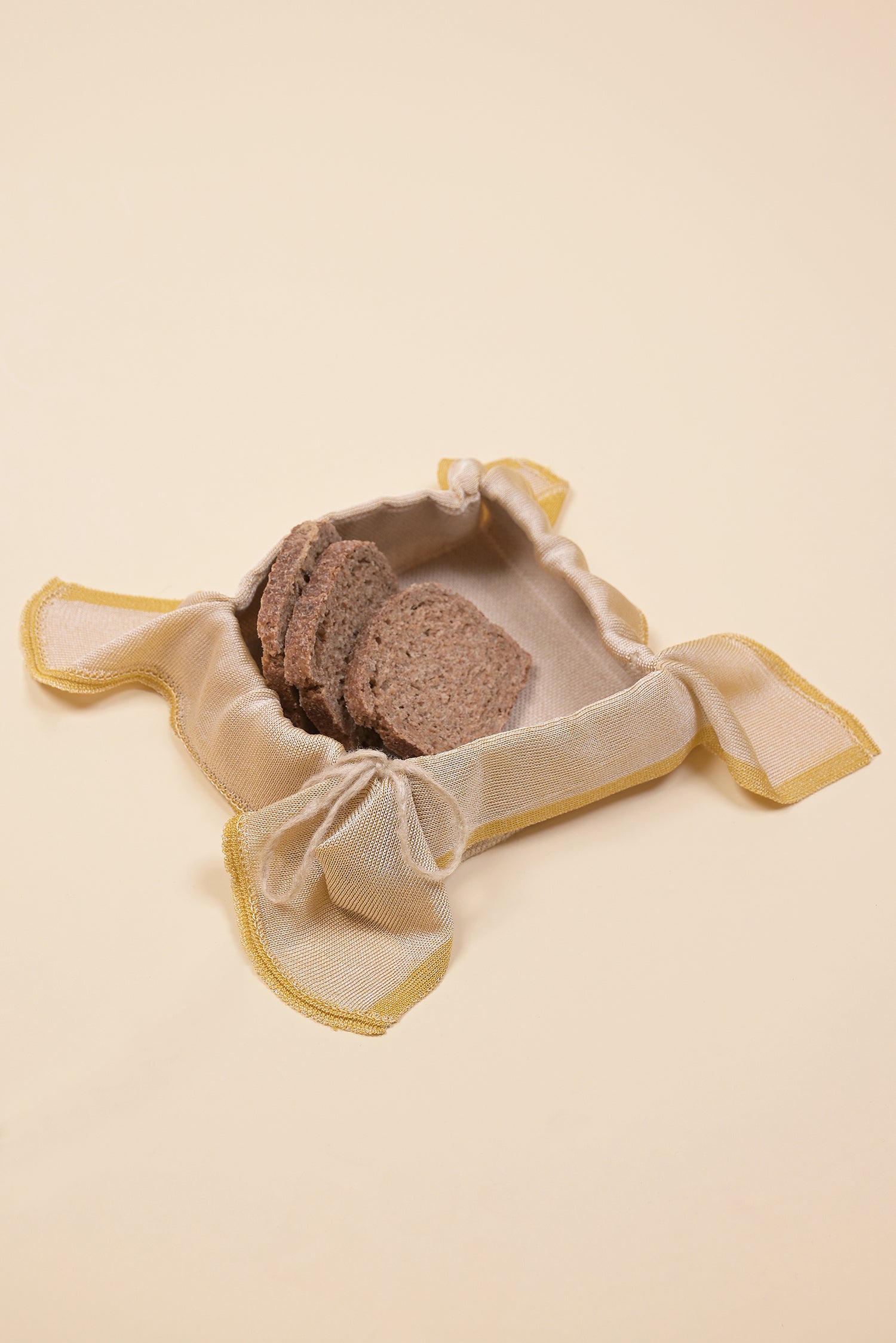 side view of yellow and beige organic cotton, hemp and viscose knit bread basket with bread