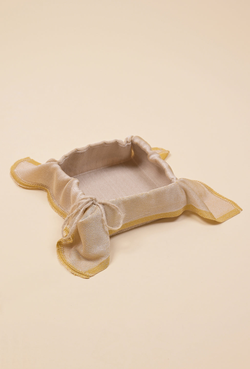 front side view of yellow and beige organic cotton, hemp and viscose knit bread basket with beige background