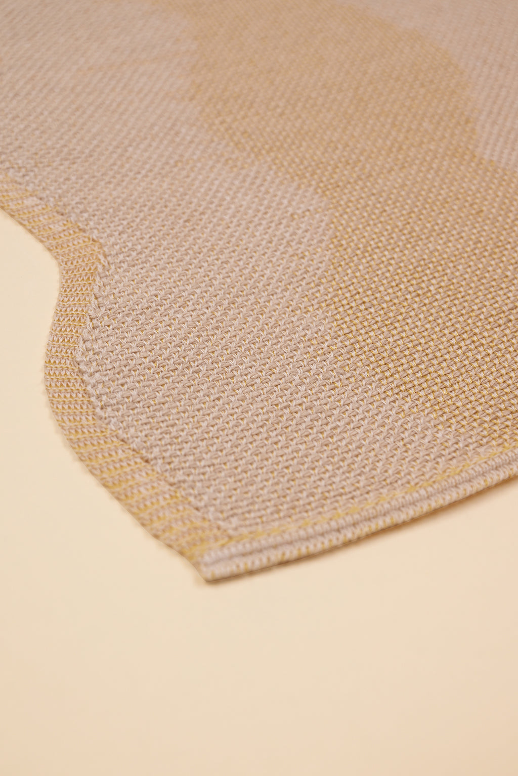 corner of beige and yellow knit organic cotton and hemp table mat with wavy pattern