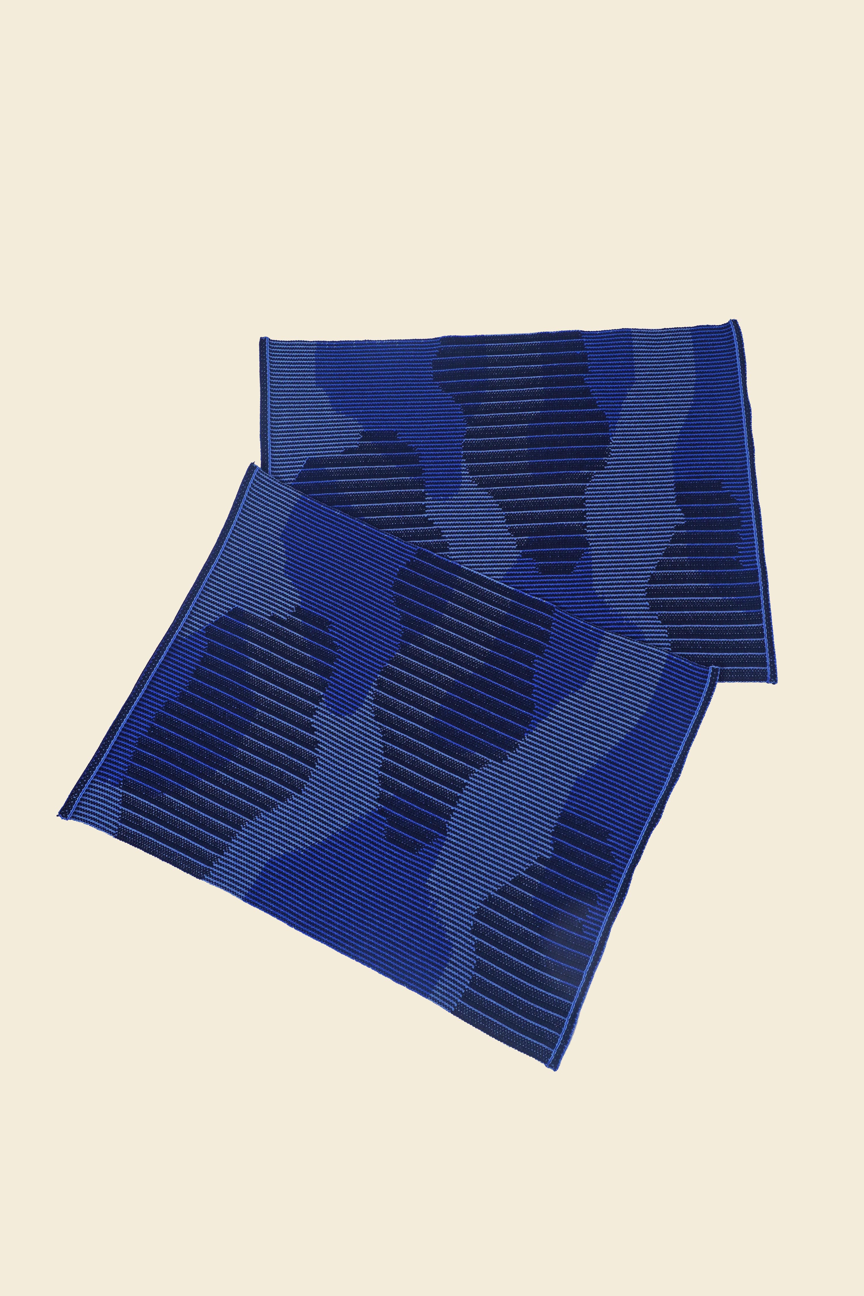 top view of blue knit organic cotton table mat with abstract design in pair