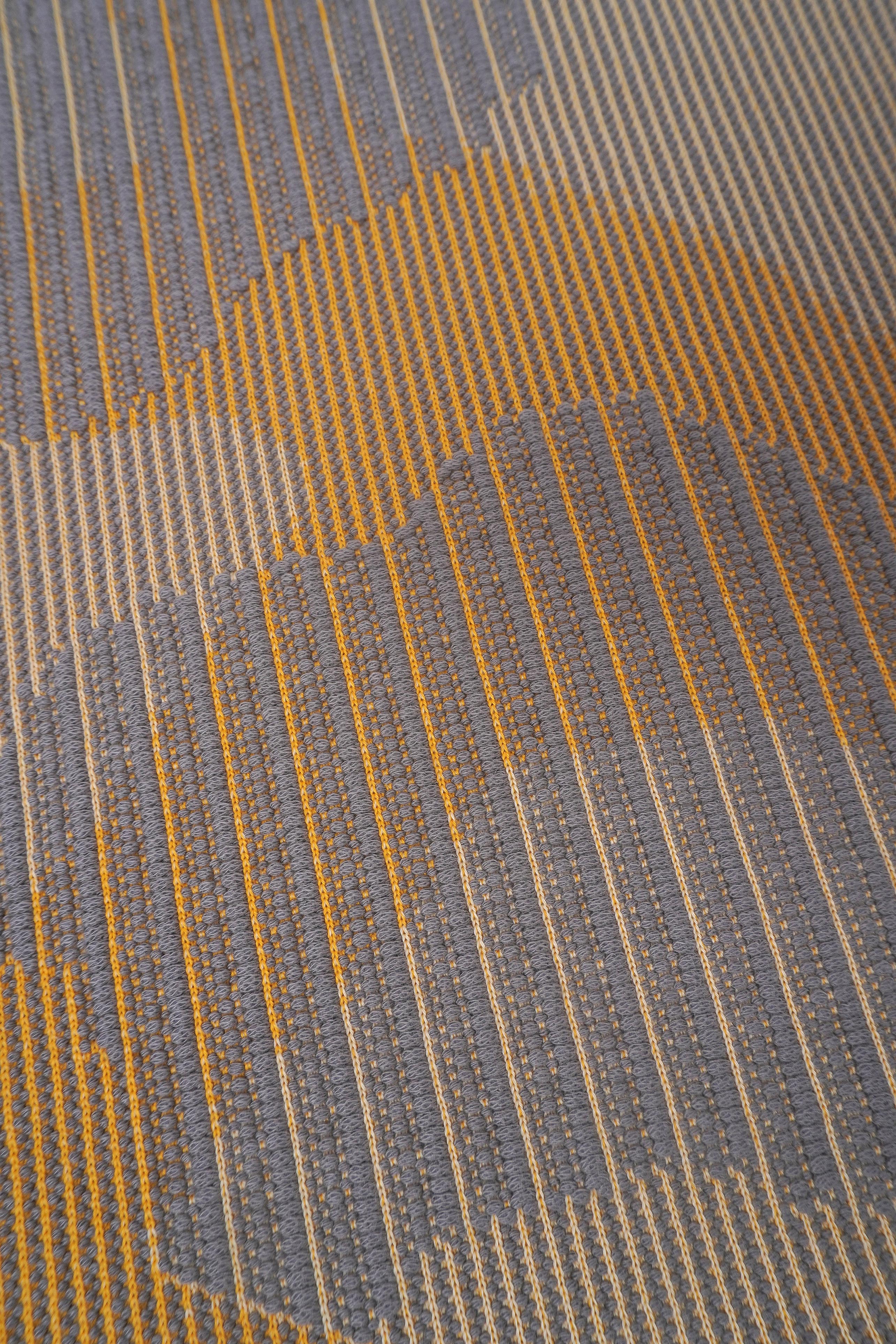 detail of yellow knit organic cotton table mat with abstract design