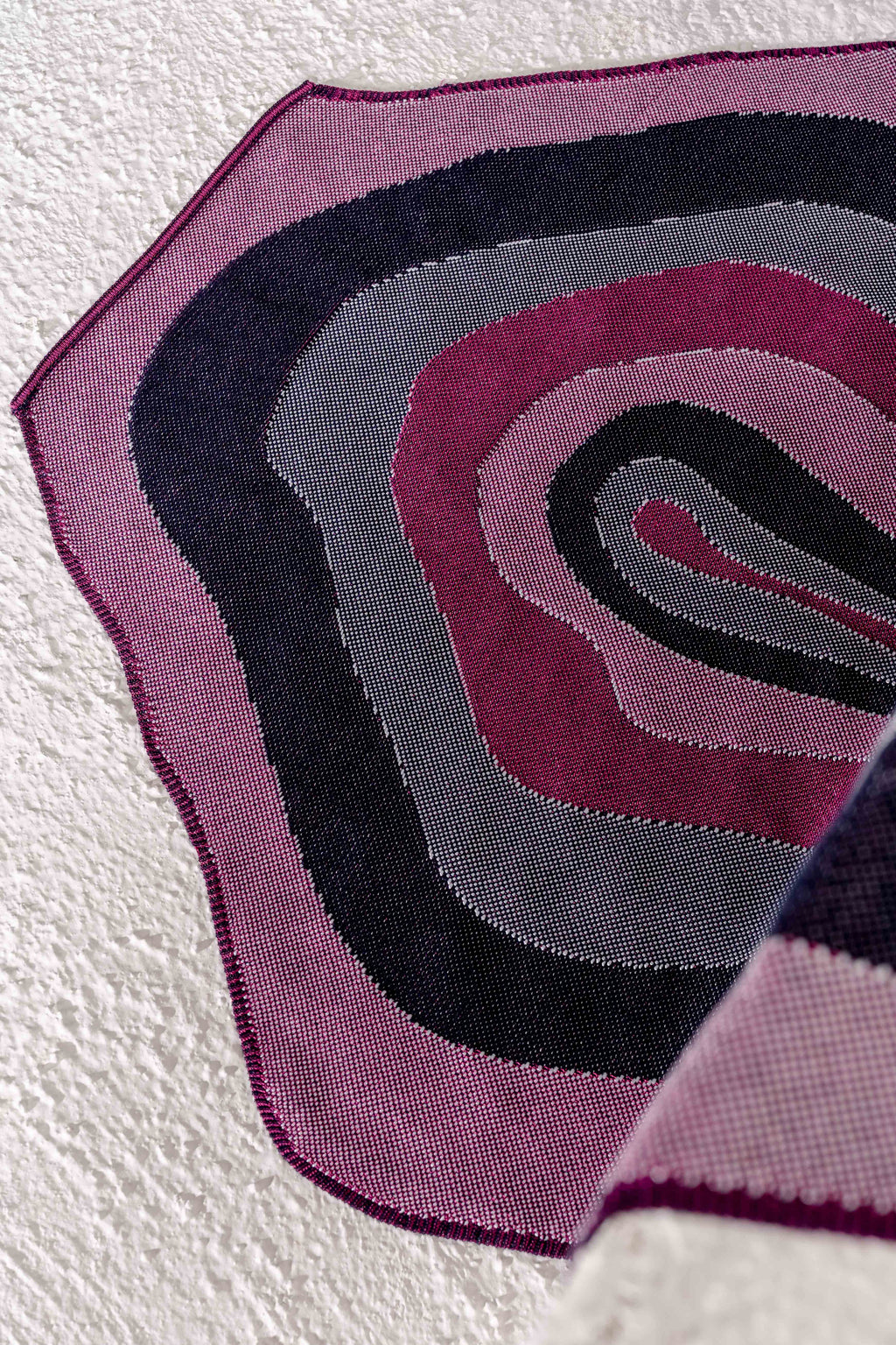 close-up of organic cotton knit tablecloth with curved edges in purple and navy