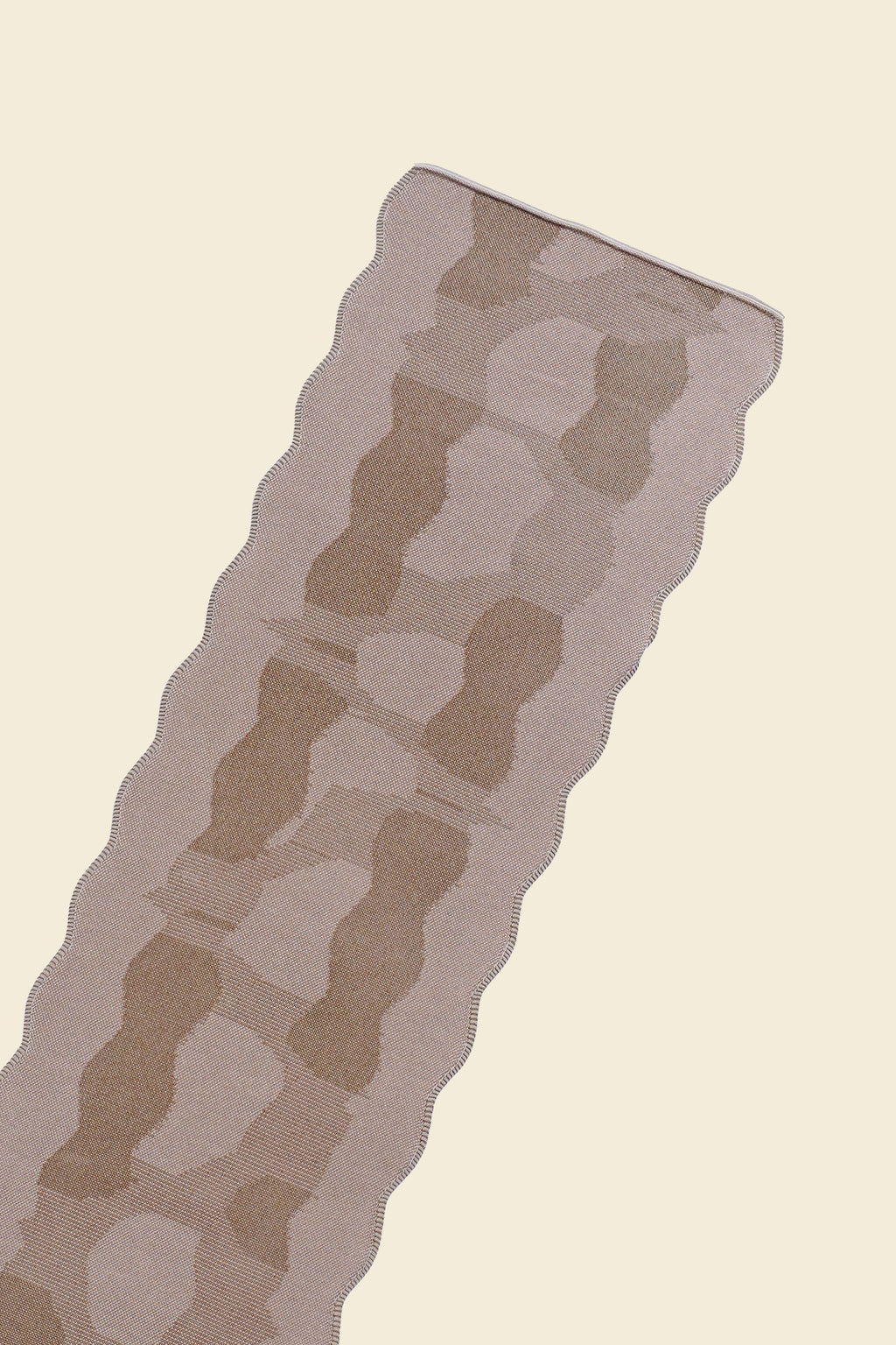 top close-up of beige knit organic cotton and viscose table runner with abstract pattern and wavy edges