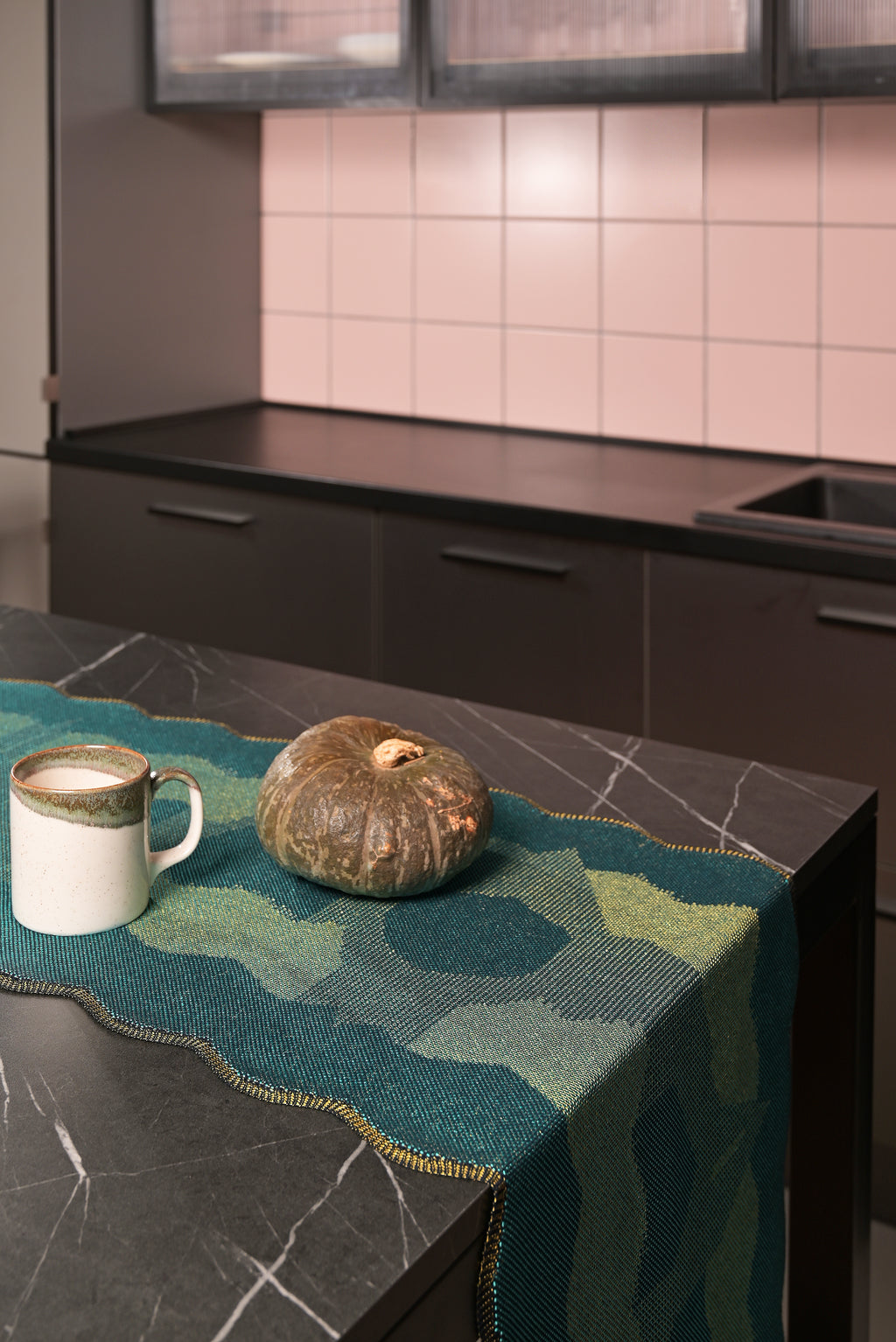 side view of green knit organic cotton and viscose table runner with abstract pattern and wavy edges kitchen display