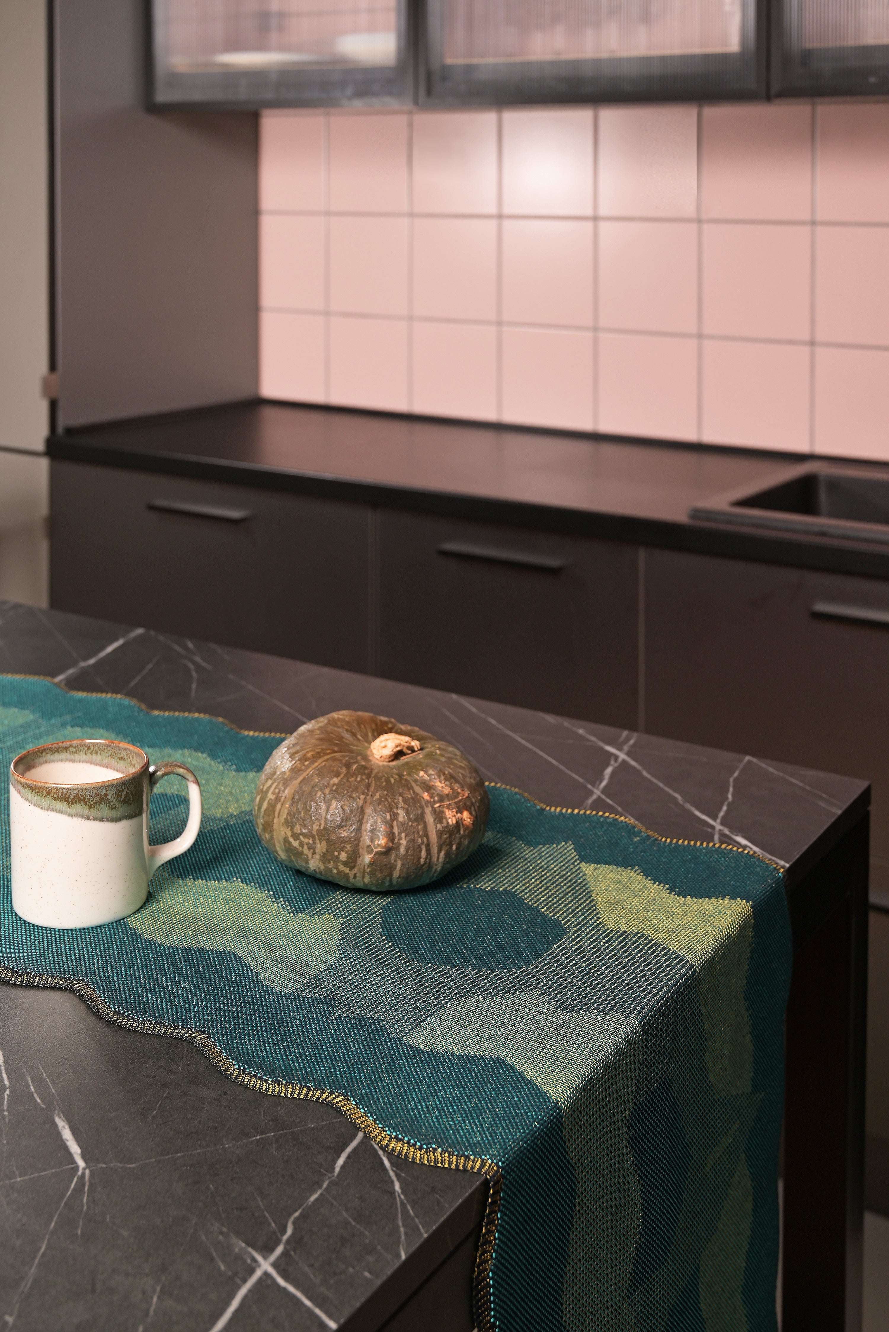 side view of green knit organic cotton and viscose table runner with abstract pattern and wavy edges kitchen display