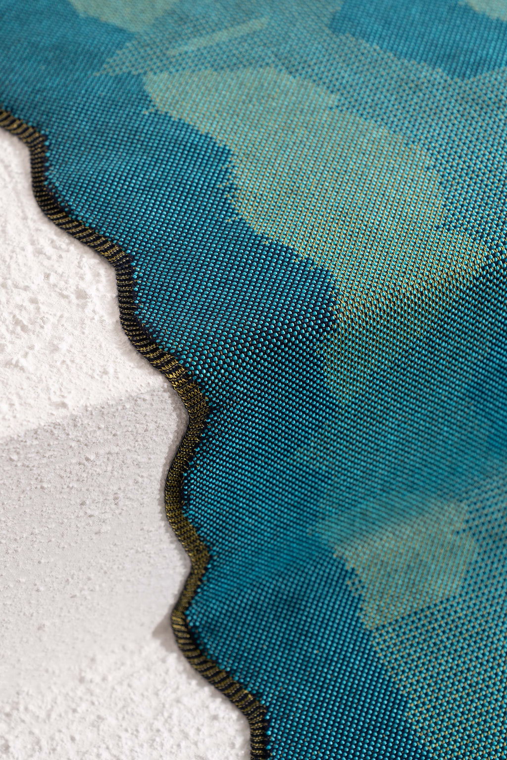 side detail of green knit organic cotton and viscose table runner with abstract pattern and wavy edges