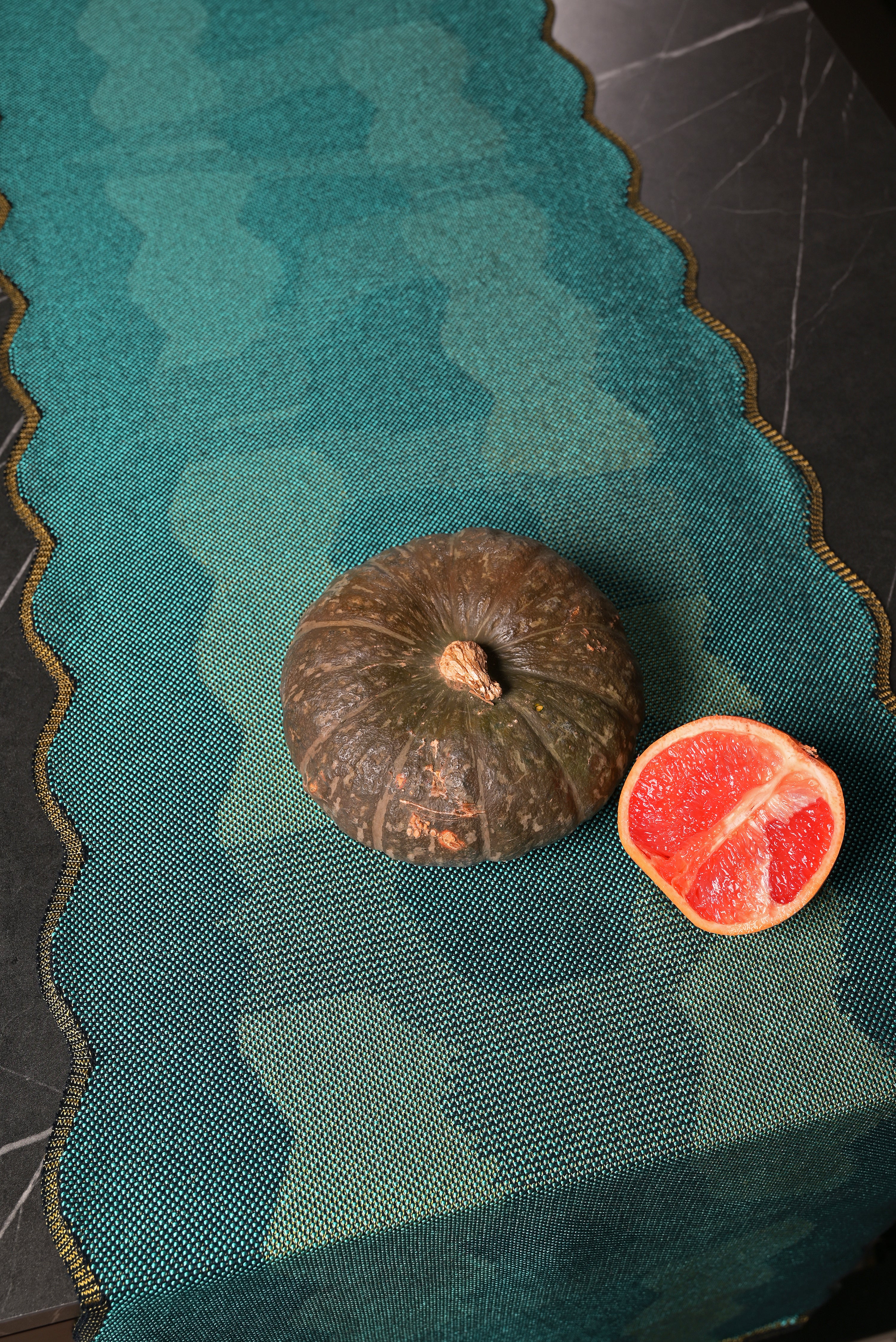 top detail view of green knit organic cotton and viscose table runner with abstract pattern and wavy edges