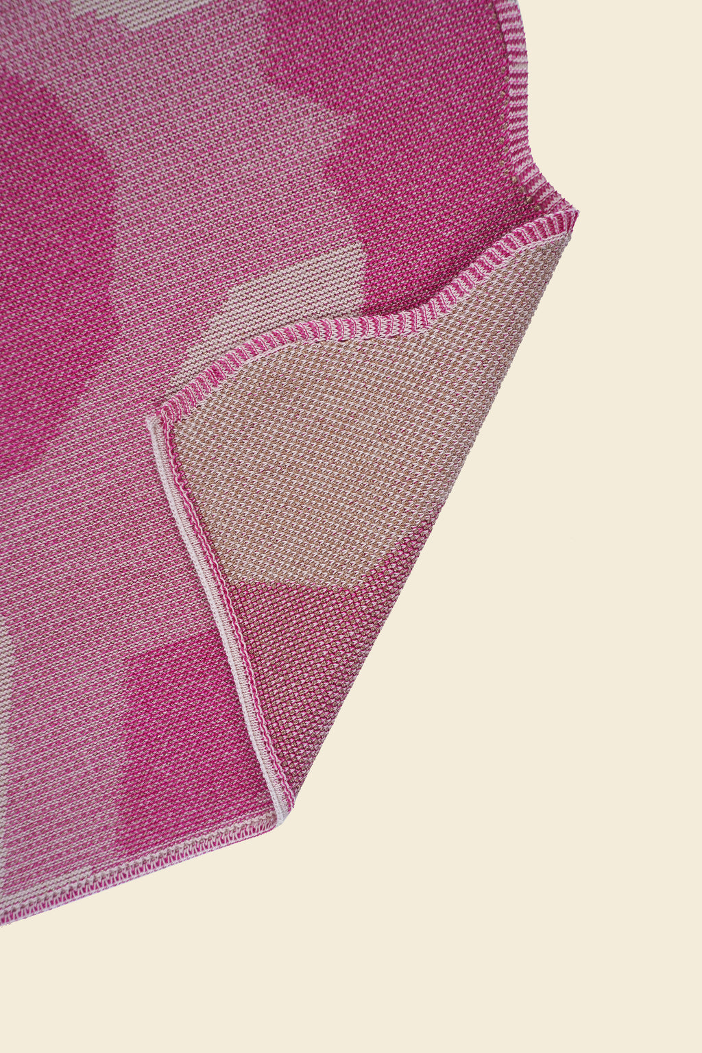 corner of pink knit organic cotton and viscose table runner with abstract pattern and wavy edges