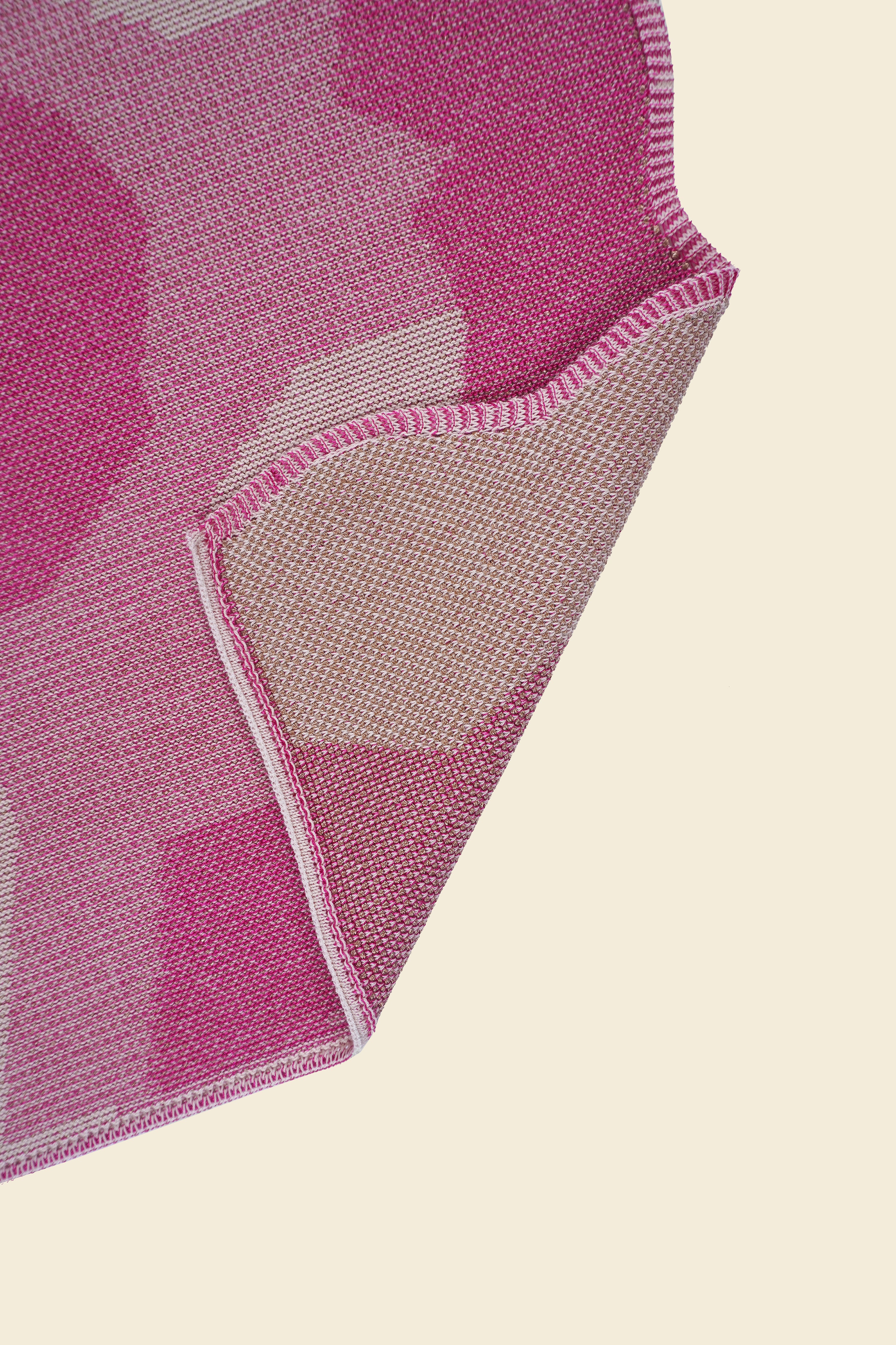 corner of pink knit organic cotton and viscose table runner with abstract pattern and wavy edges