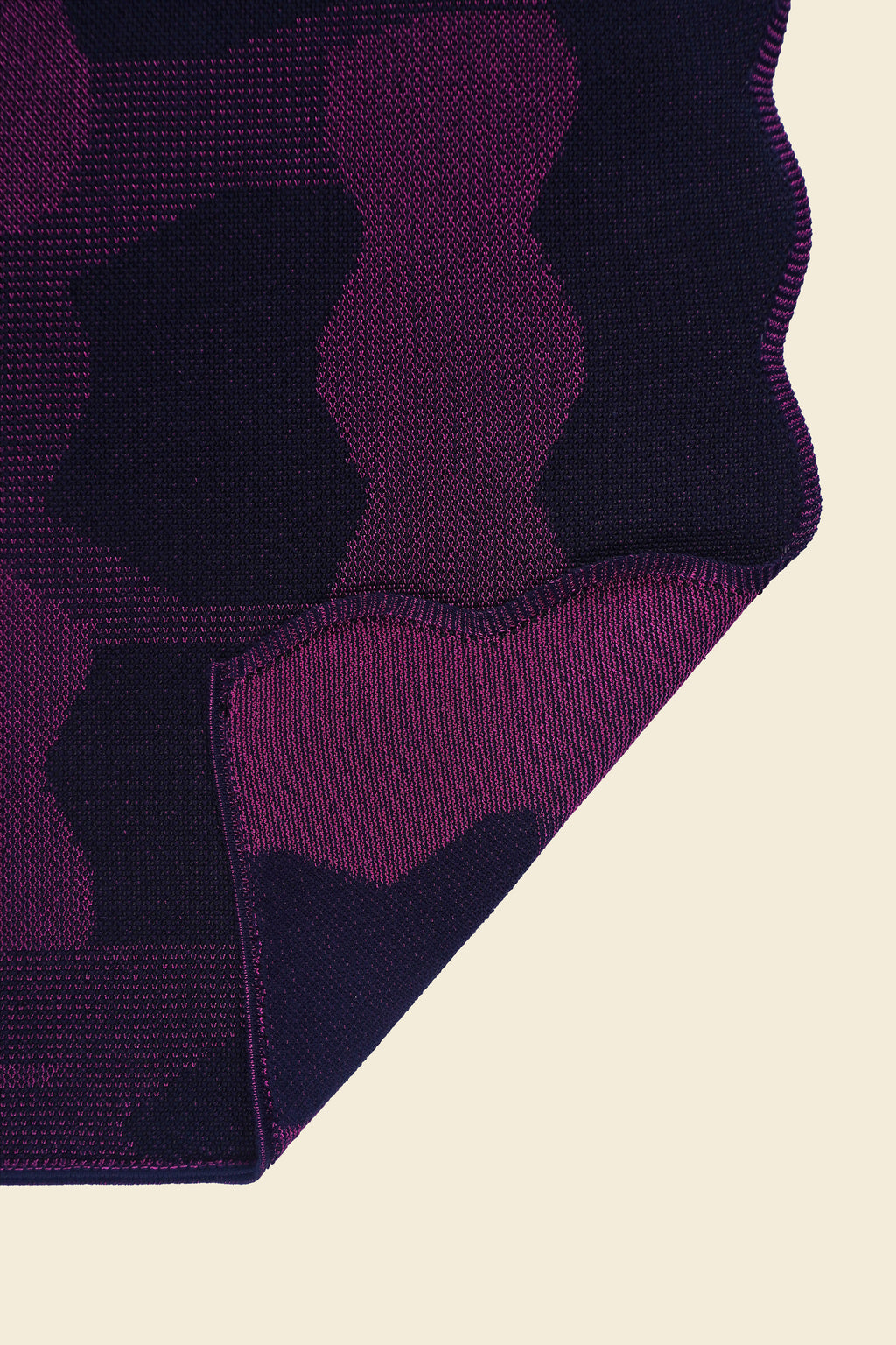 corner of purple knit organic cotton and viscose table runner with abstract pattern and wavy edges
