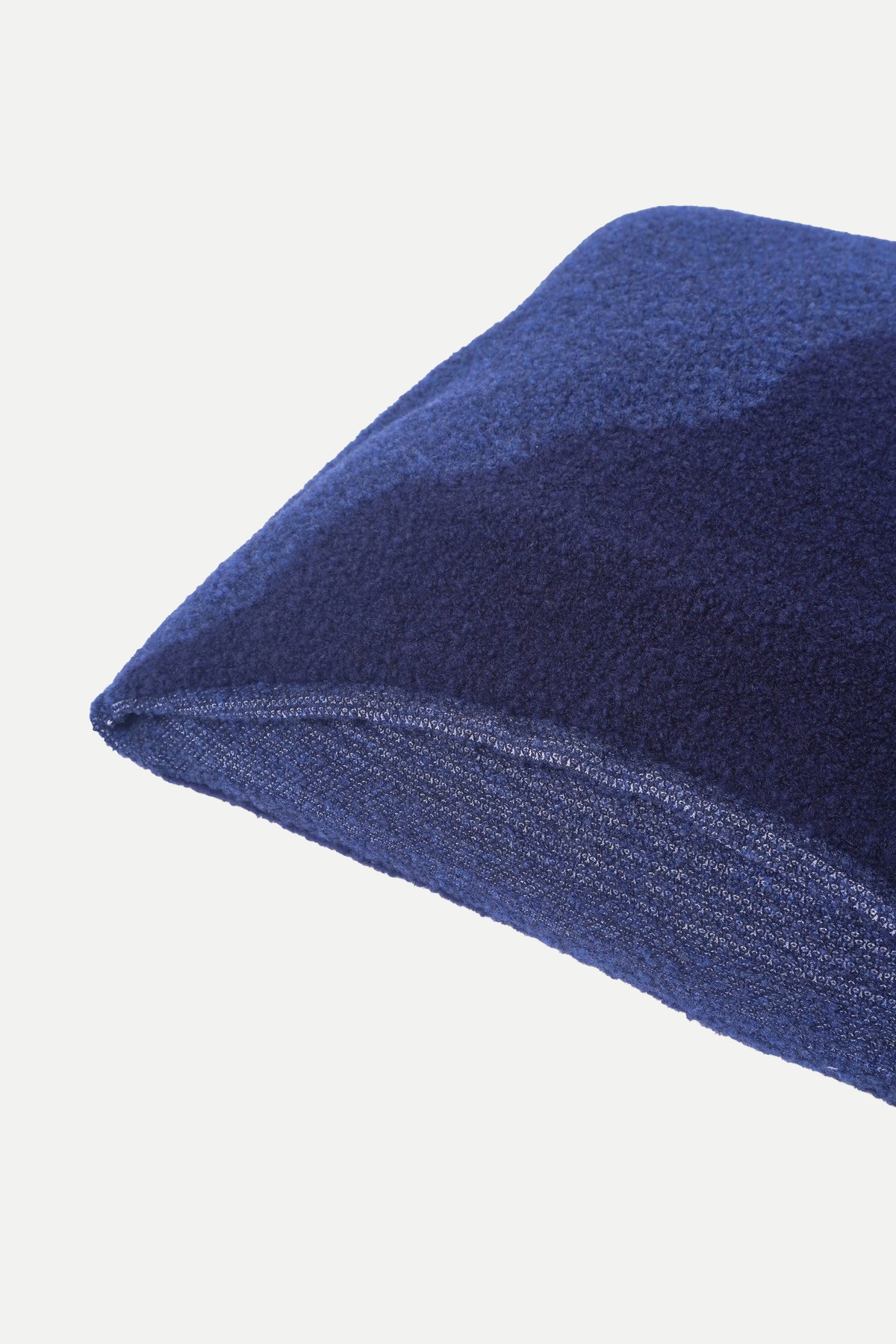 [blue/navy] close-up of the corner and boucle knit texture on the blue and navy plush knit pillowcase