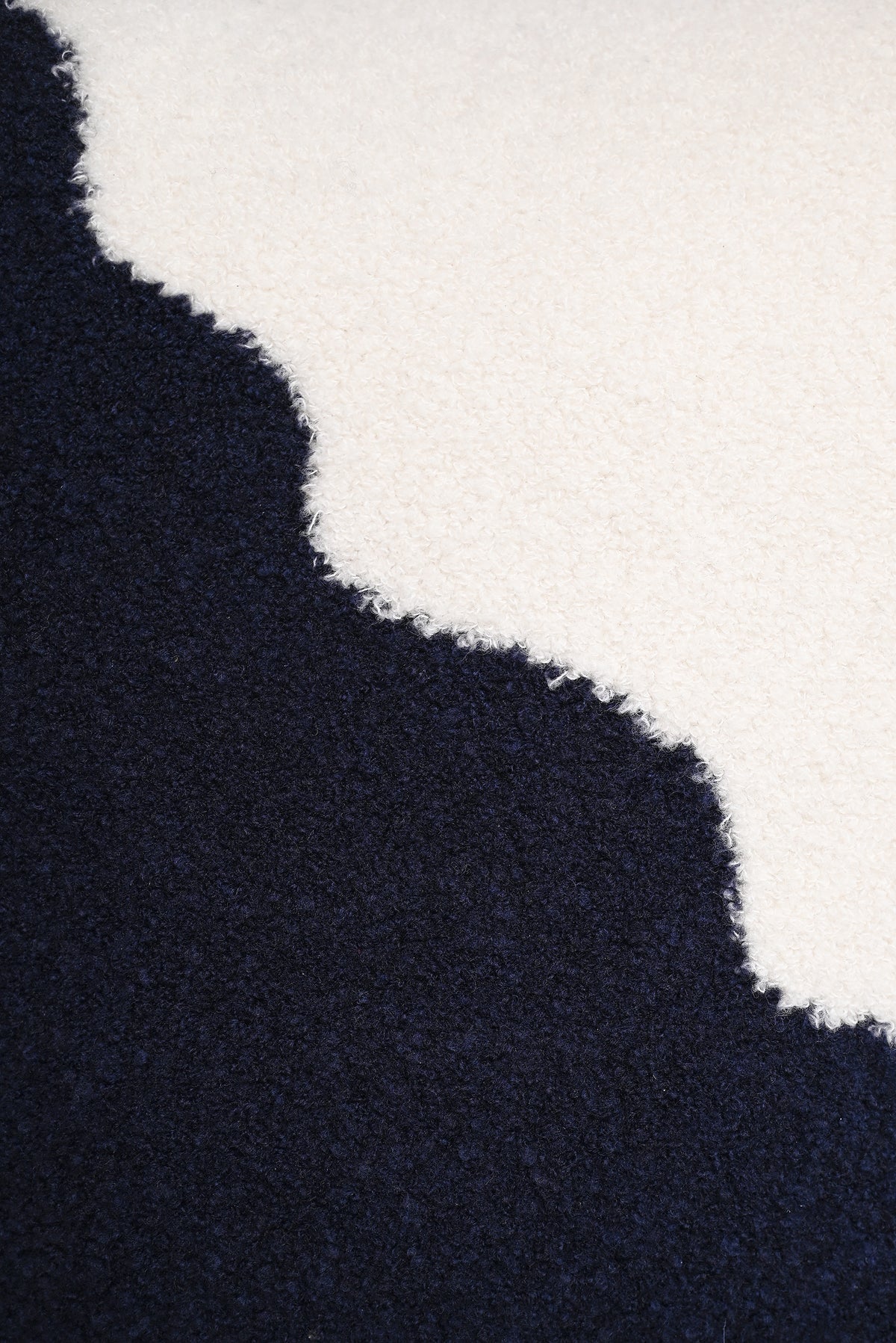[off-white/navy] close-up of the corner tie detail on the off-white and navy plush knit pillowcase