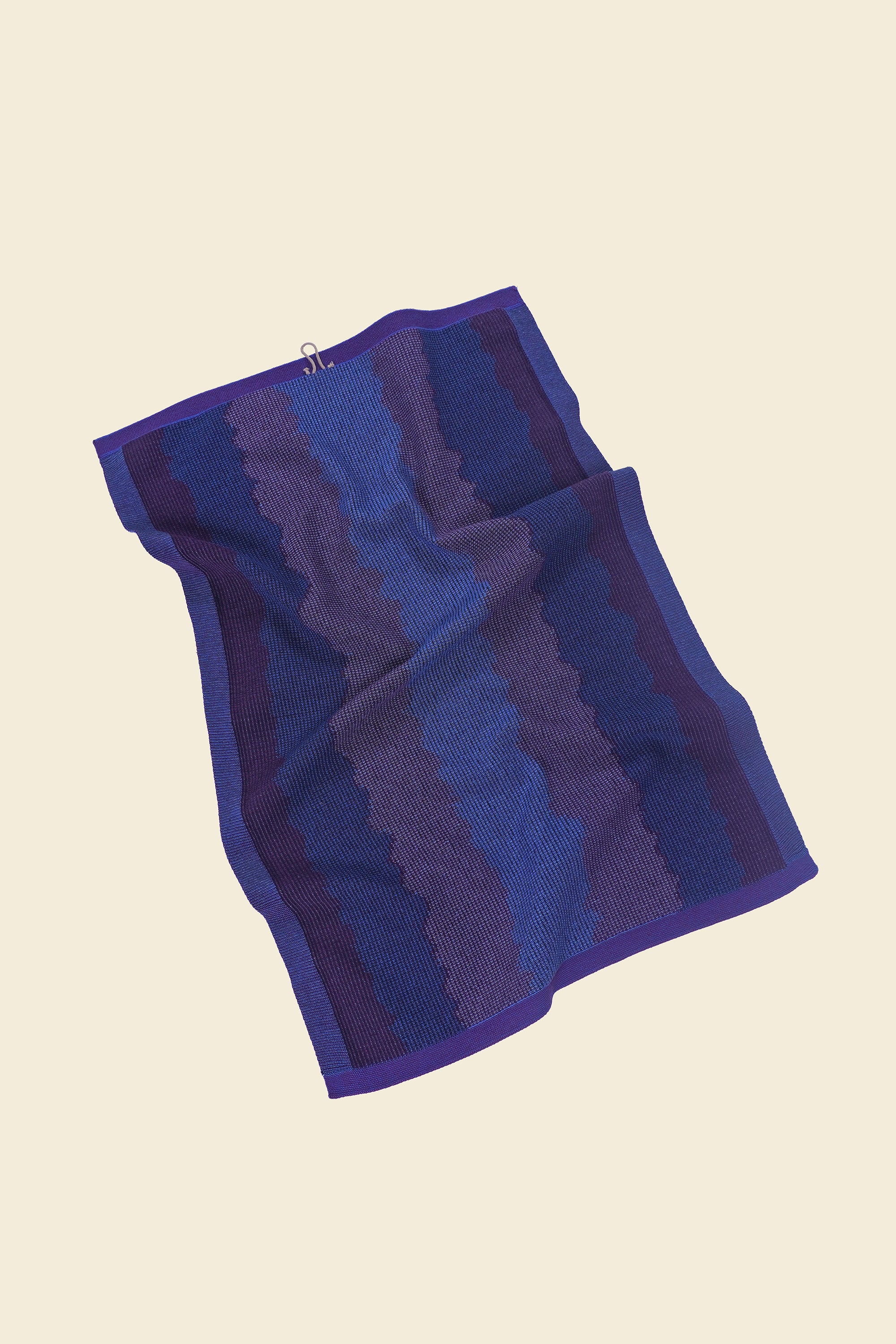 back view of purple knit organic cotton kitchen towel with wavy pattern with folds
