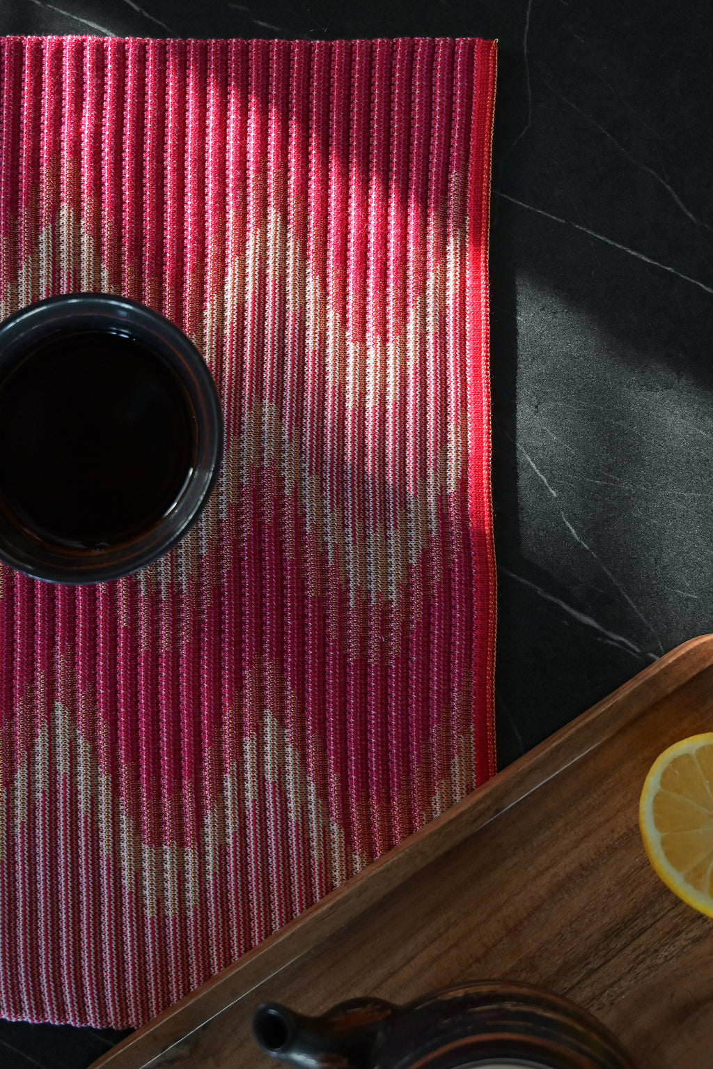 corner detail of red/yellow knit table mat in organic cotton and viscose with wavy pattern