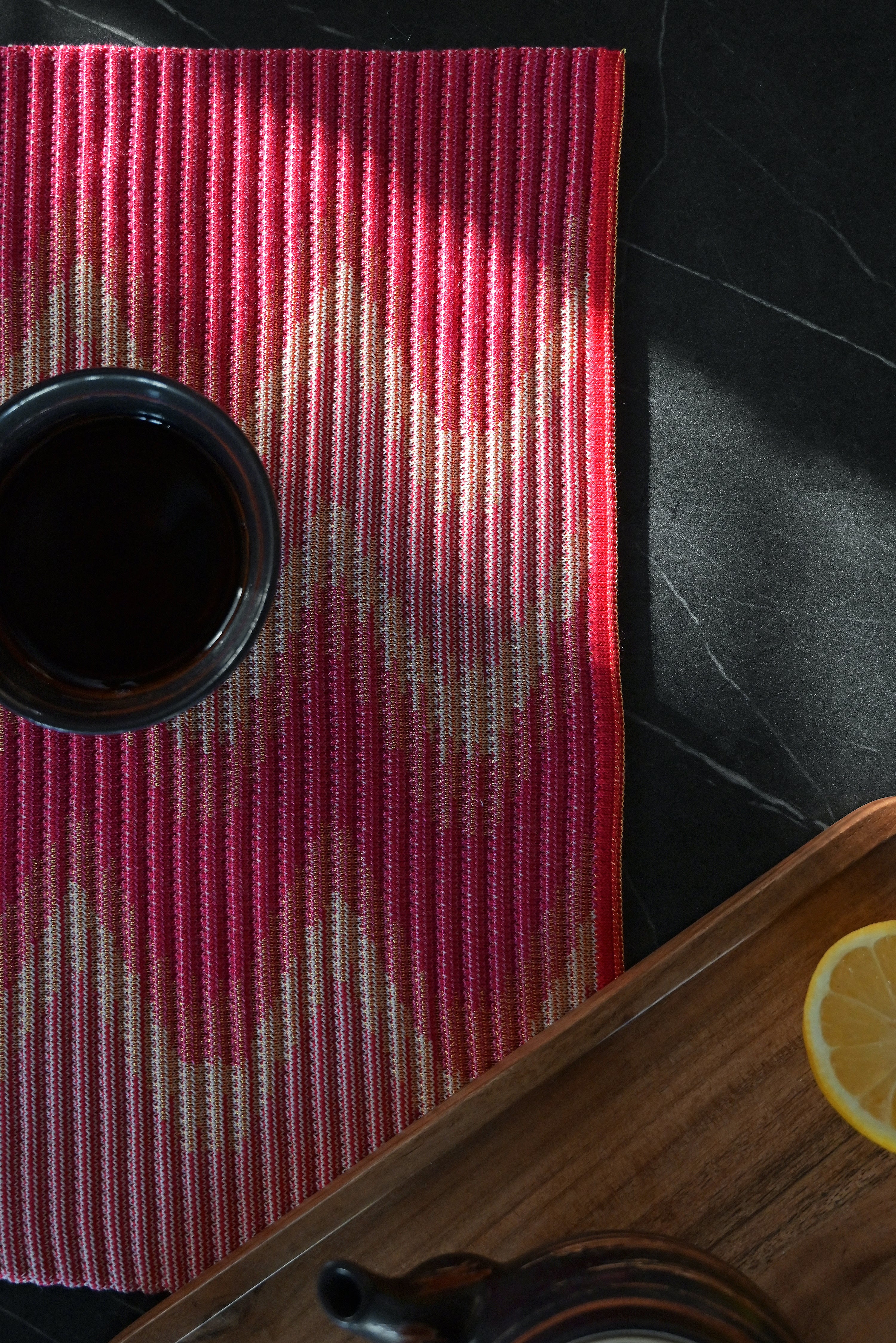 corner detail of red/yellow knit table mat in organic cotton and viscose with wavy pattern