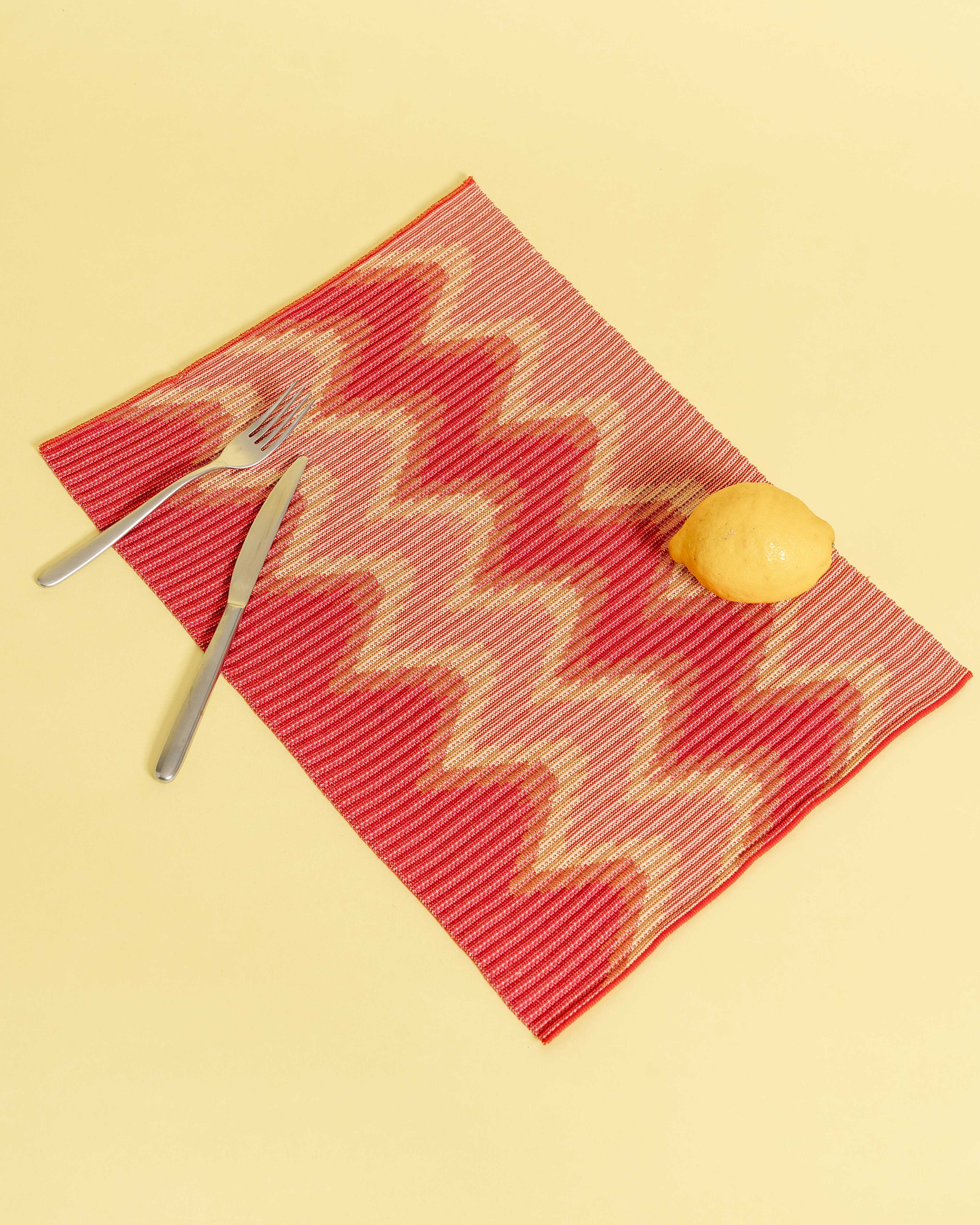 top view of red/yellow knit table mat in organic cotton and viscose with wavy pattern with yellow background