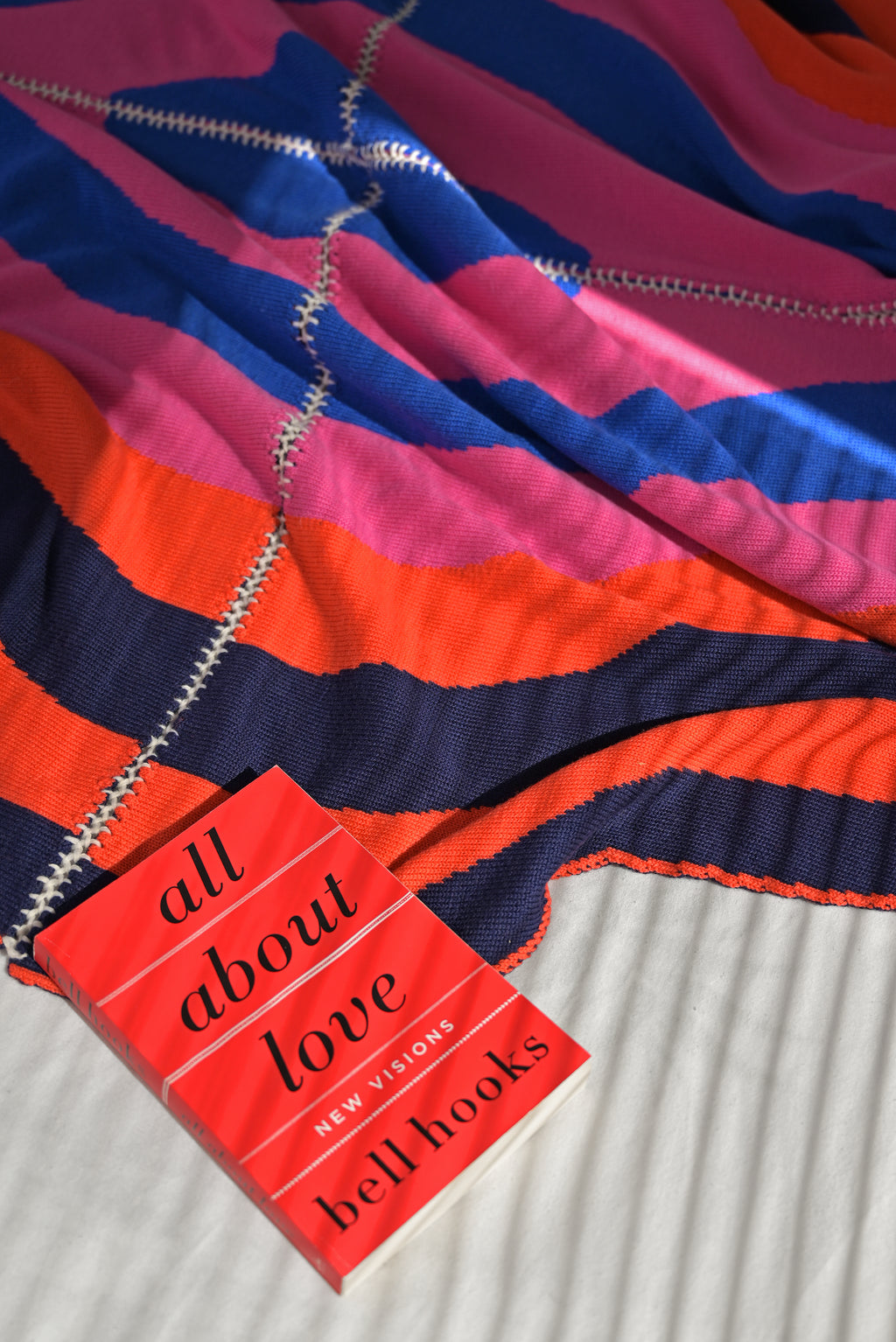 dark wavy knit wool blanket with book and with hand-stitched seam in blue, pink, red and navy 