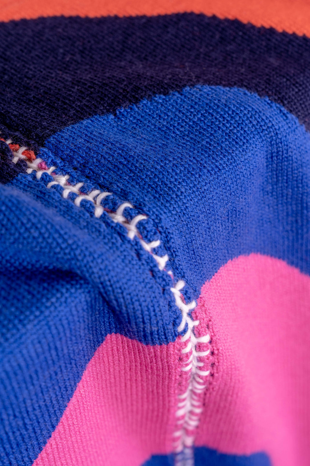 detail of dark wavy knit wool blanket with hand-stitched seam in blue, pink, red and navy 