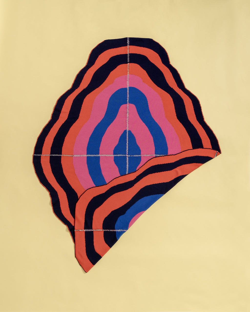 dark wavy knit wool blanket with flipped corner and with hand-stitched seam in blue, pink, red and navy 