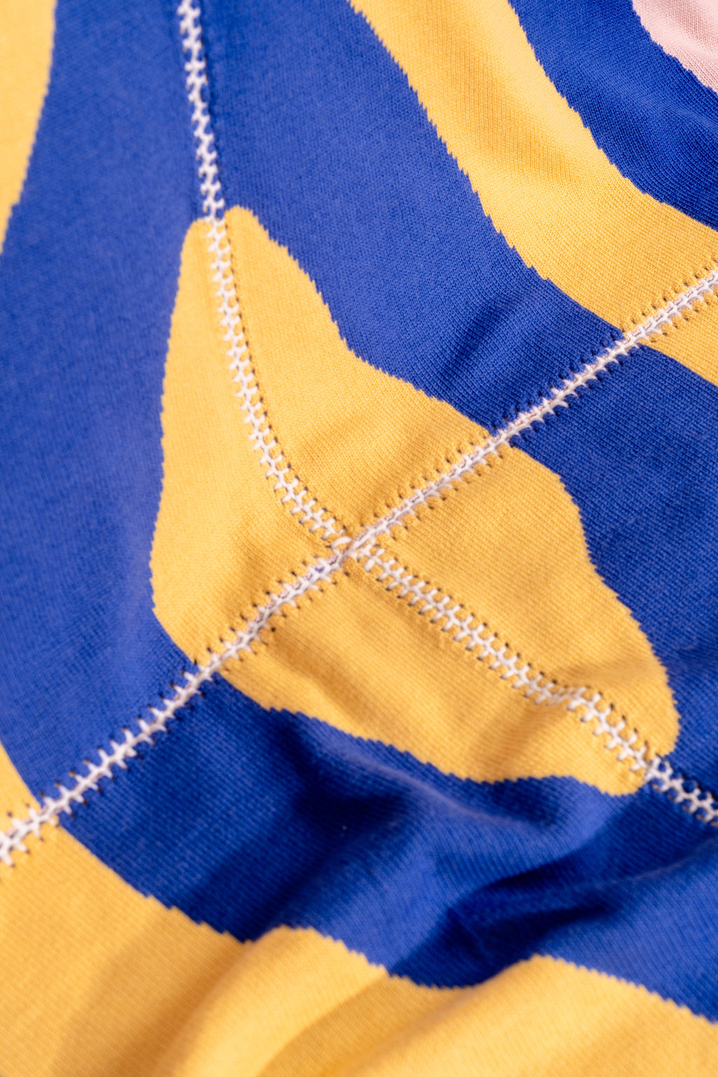 detail of light wavy knit wool blanket with hand-stitched seam in blue, yellow, pink, and camel 