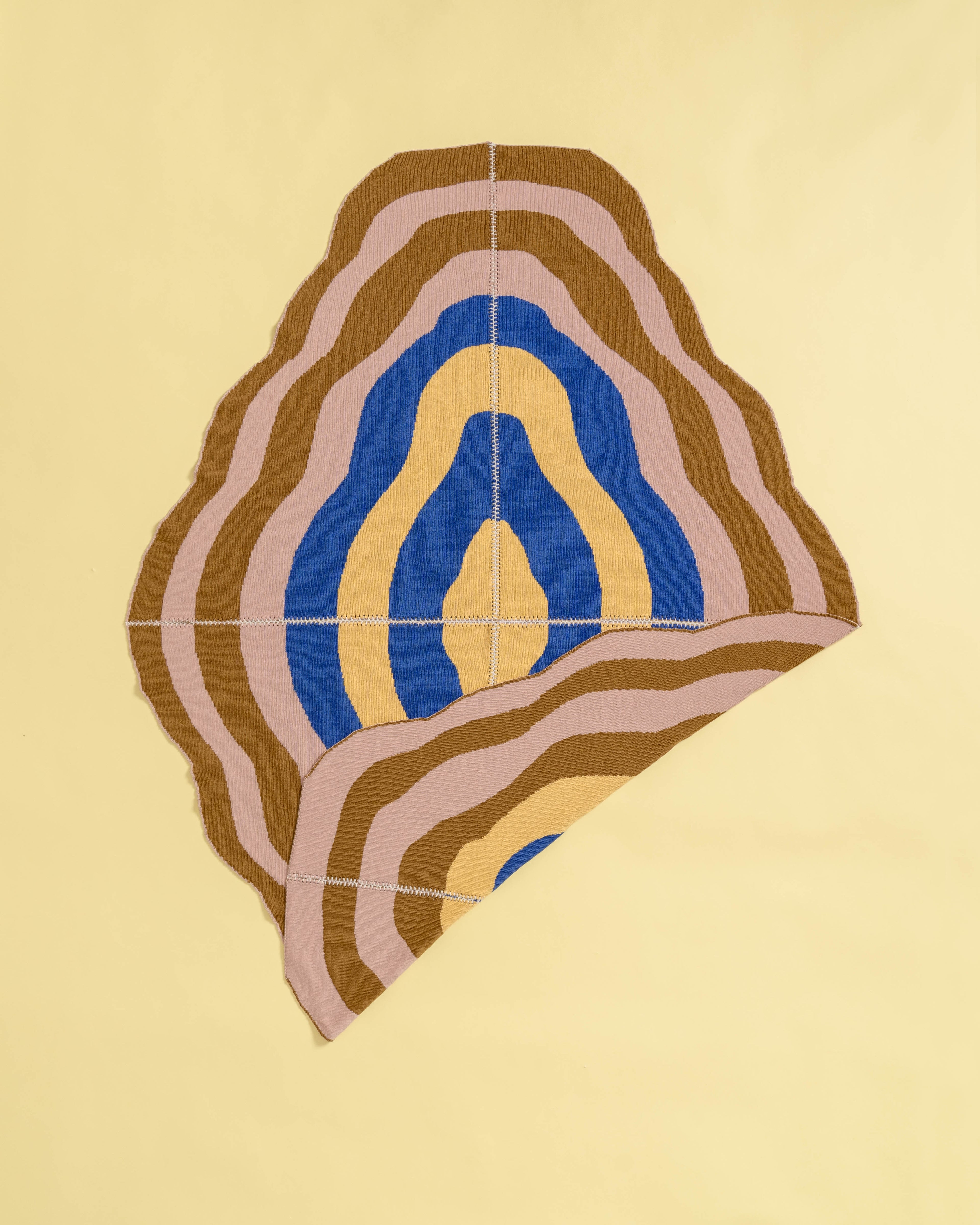 light wavy knit wool blanket with flipped corner and hand-stitched seam in blue, yellow, pink, and camel 