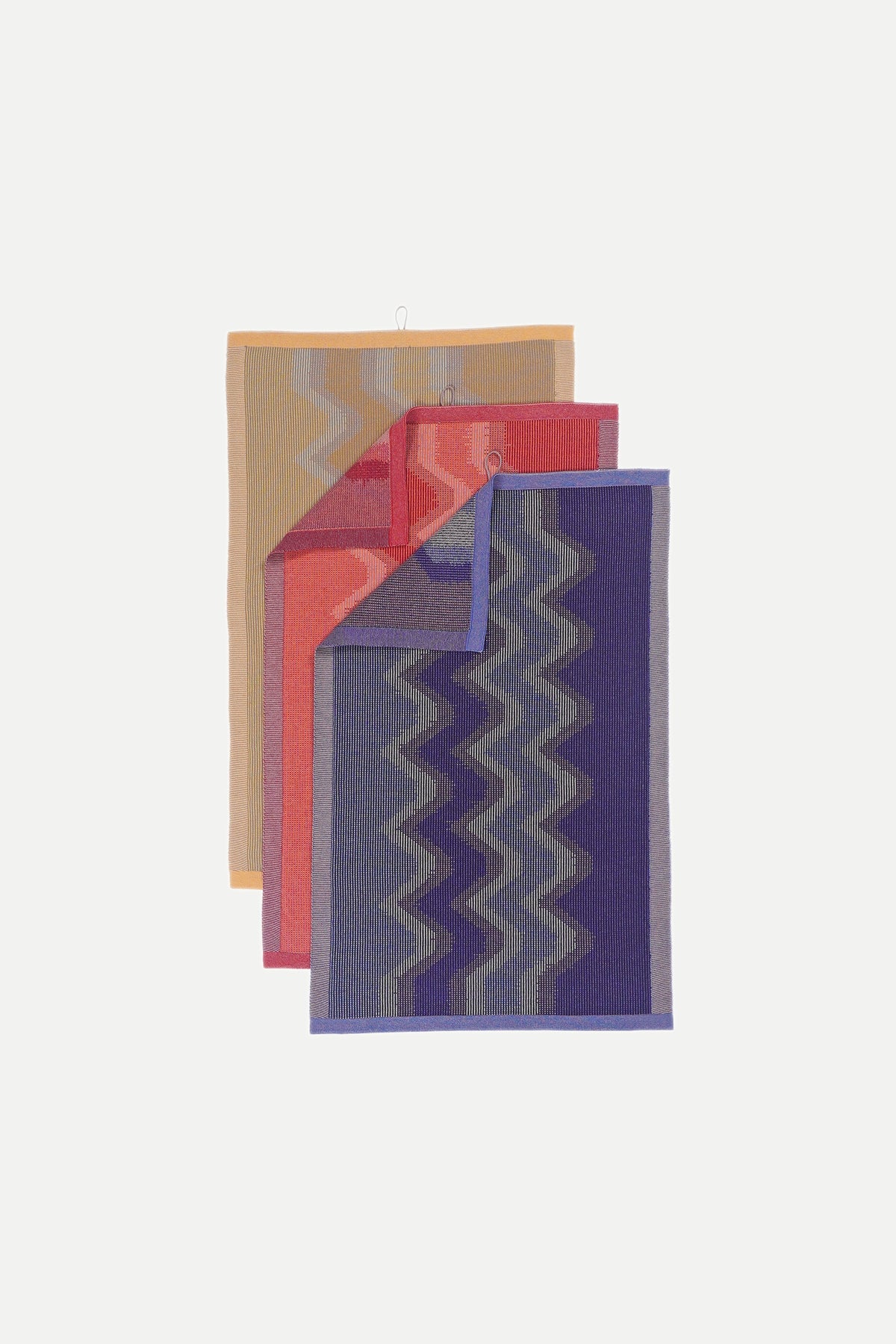 yellow, red and purple knit organic cotton kitchen towel set fanned out in a flat lay